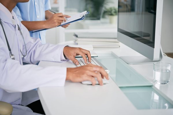 Cropped image of doctor working on computer at his table
